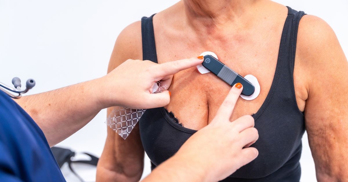 Healthcare professional applying wearable blood sensor patch to patient's chest for monitoring