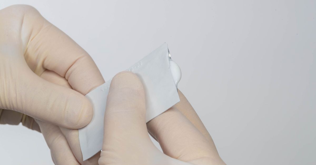 Skin barrier creams applied from single-use sachet by gloved hands.