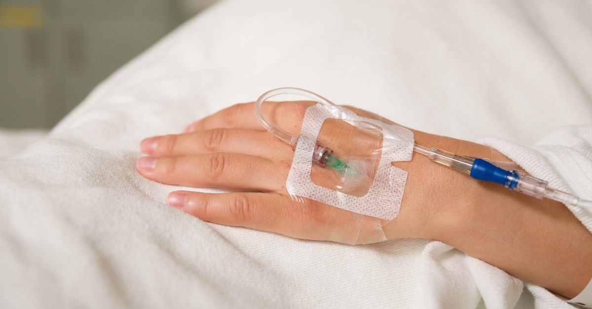 Close-up of IV securement dressings applied over intravenous line on back of hand.